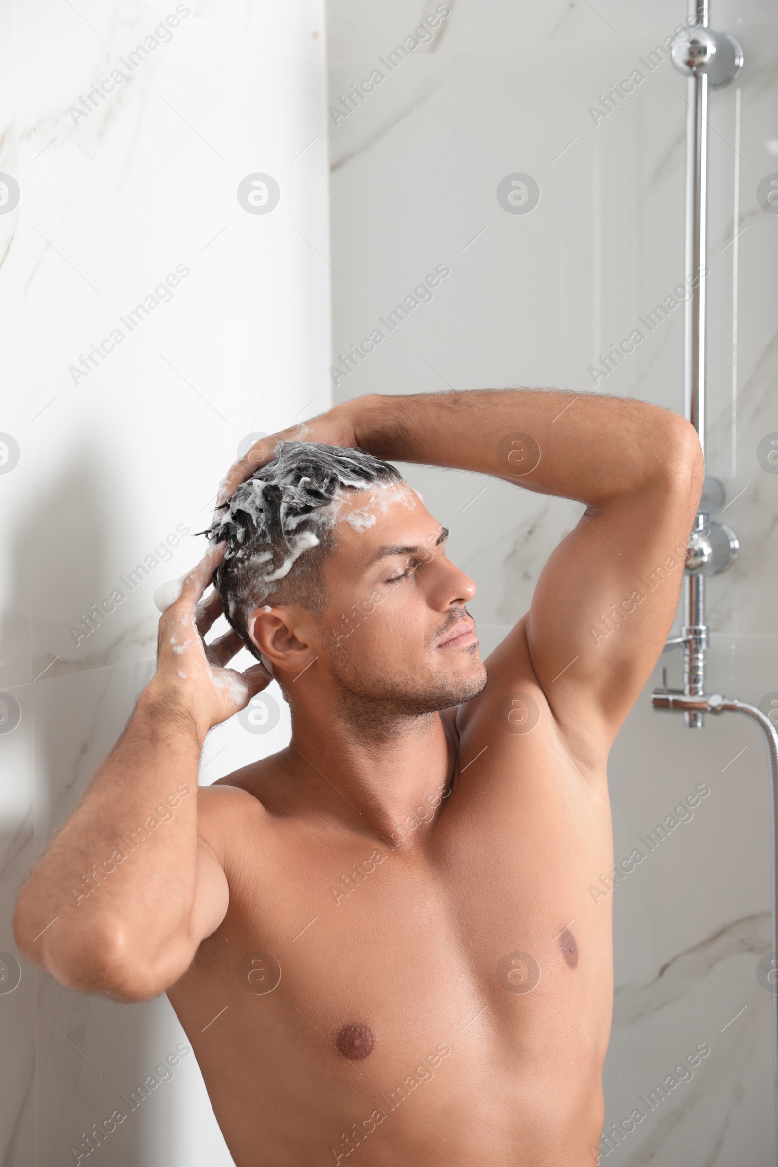 Photo of Handsome man washing hair in shower at home