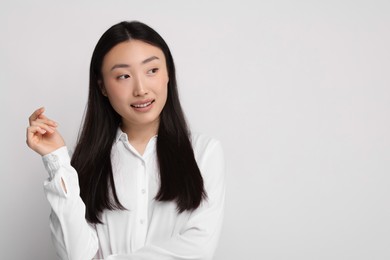 Portrait of smiling woman on light background. Space for text