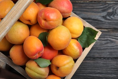 Photo of Many fresh ripe apricots in wooden basket on table, top view