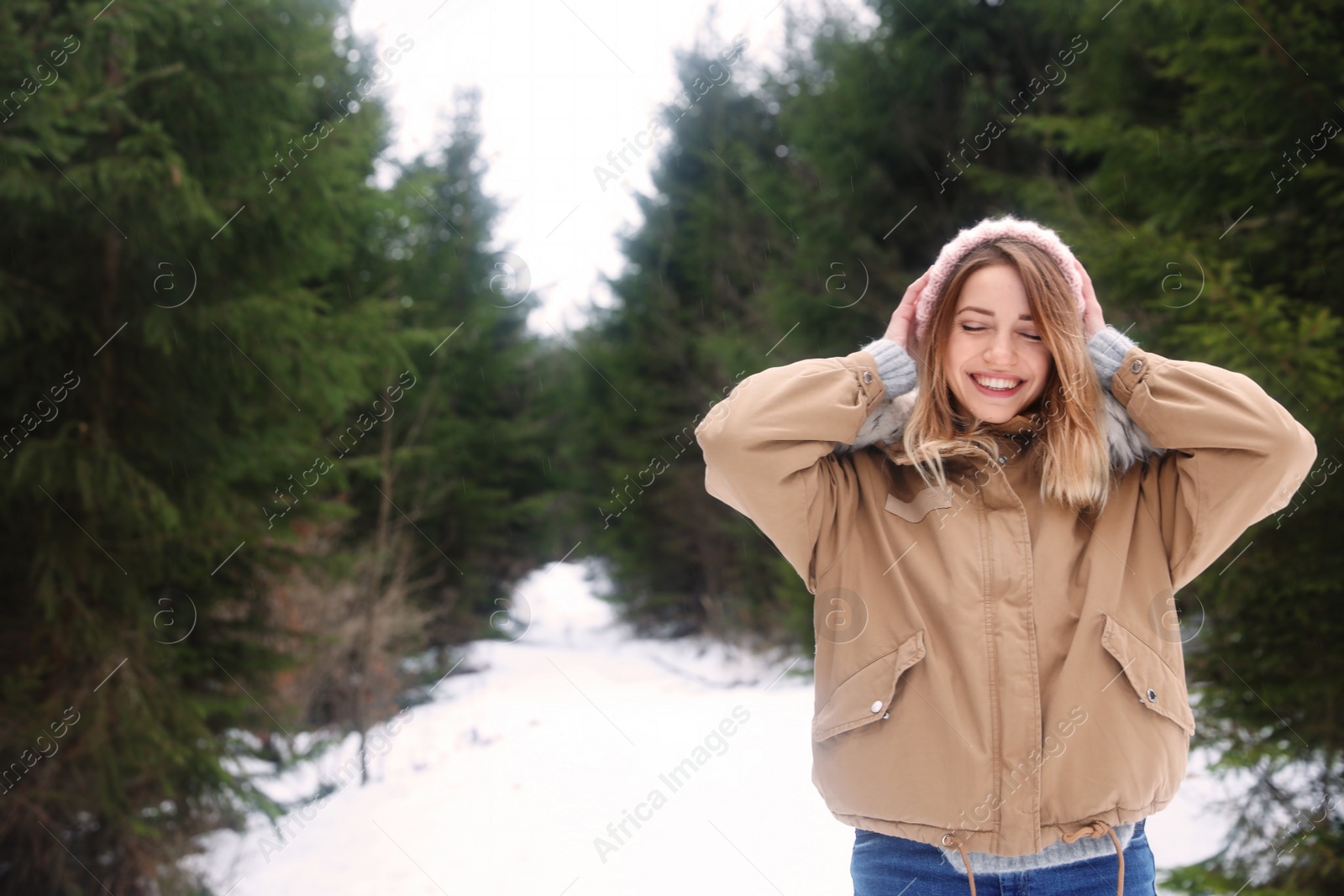 Photo of Young woman in snowy conifer forest, space for text. Winter vacation