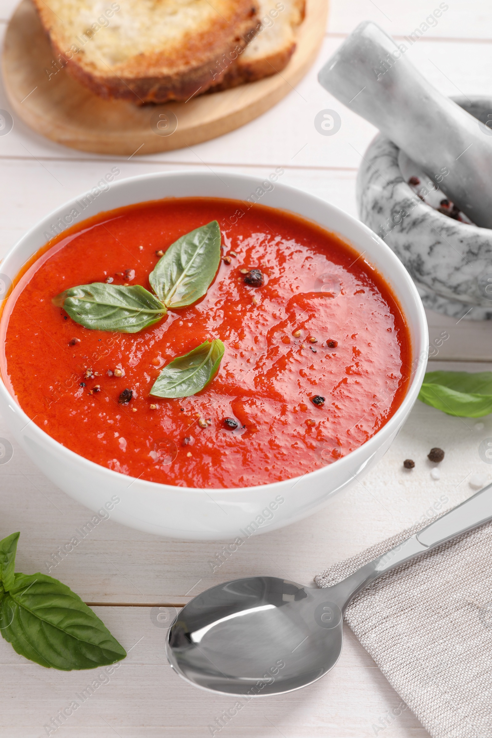 Photo of Delicious tomato cream soup in bowl served on white wooden table