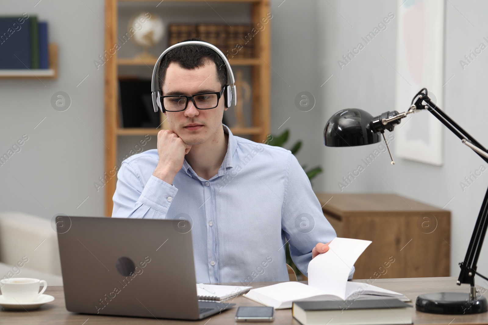 Photo of E-learning. Young man using laptop during online lesson at table indoors.