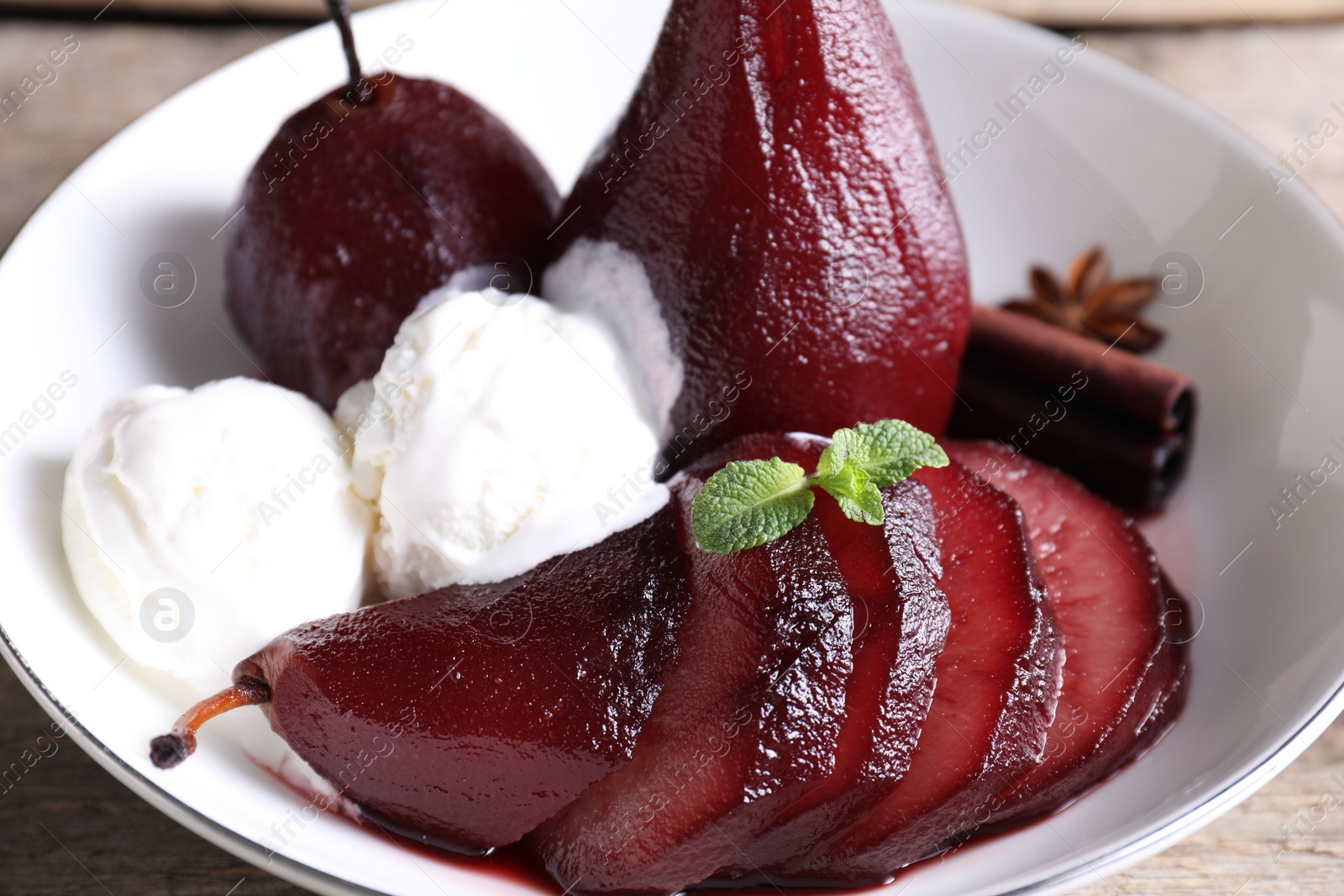 Photo of Tasty red wine poached pears and ice cream in bowl on table, closeup