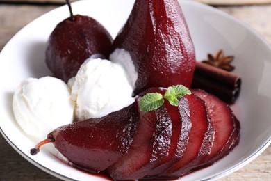 Tasty red wine poached pears and ice cream in bowl on table, closeup