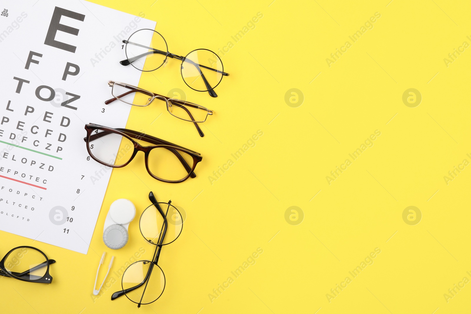 Photo of Vision test chart, glasses, lenses and tweezers on yellow background, flat lay. Space for text