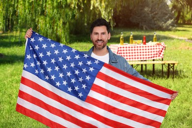 Image of 4th of July - Independence day of America. Happy man with national flag of United States having picnic in park