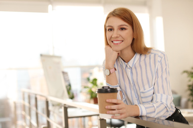 Young businesswoman with cup of coffee relaxing in office during break
