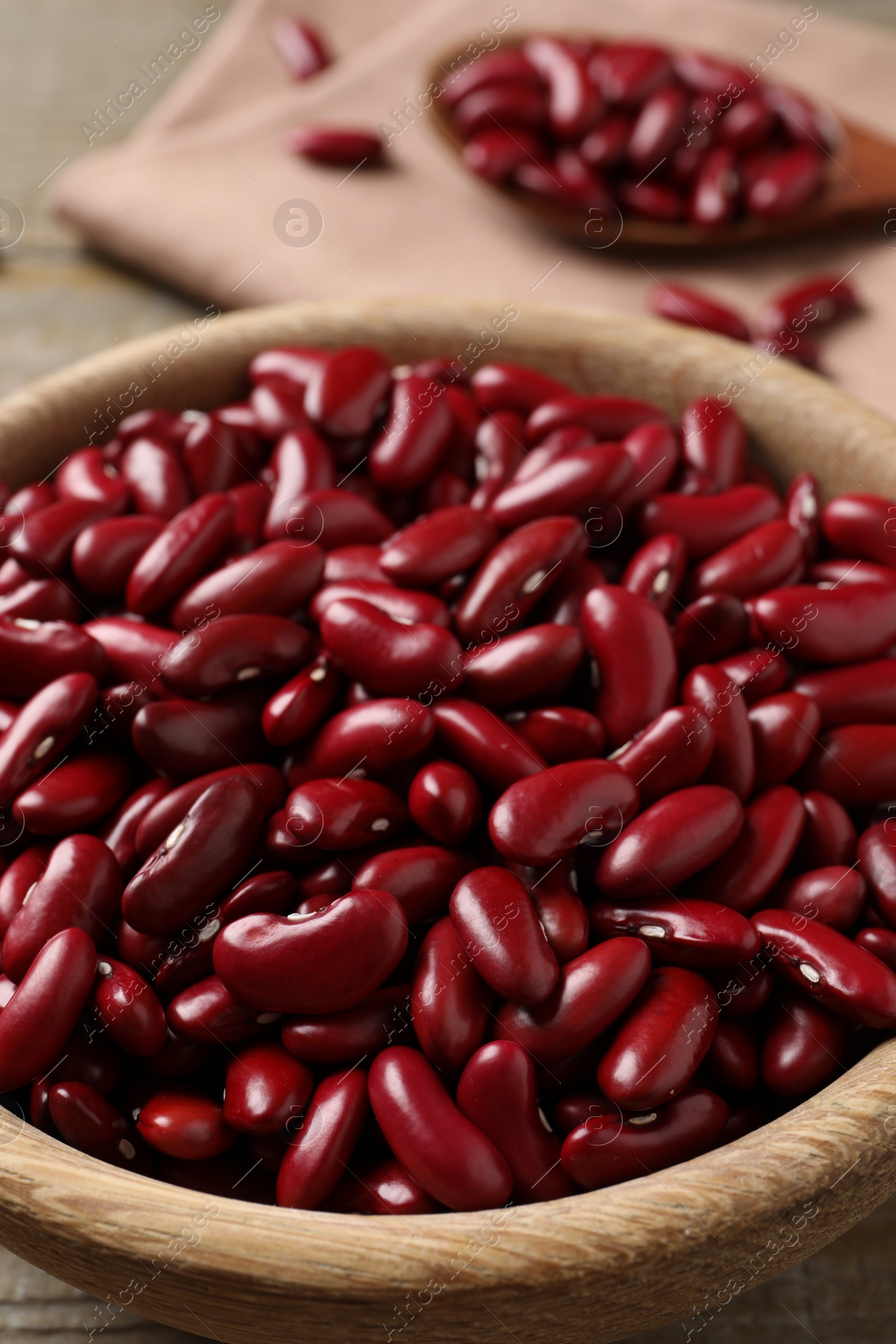 Photo of Raw red kidney beans in wooden bowl on table, closeup