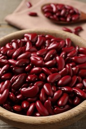 Raw red kidney beans in wooden bowl on table, closeup