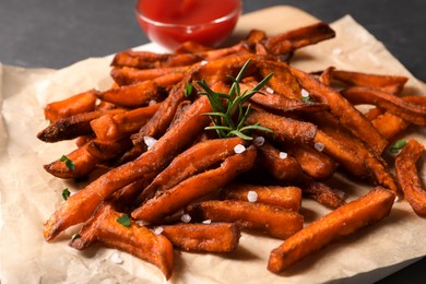 Photo of Delicious sweet potato fries and sauce on parchment paper, closeup