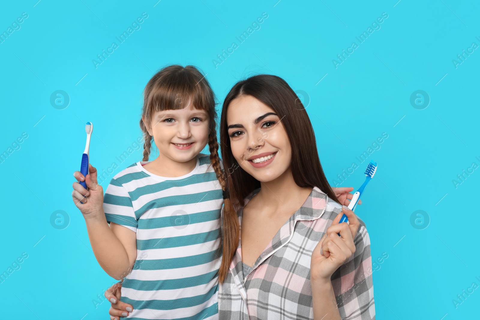 Photo of Little girl and her mother with toothbrushes on color background. Teeth care