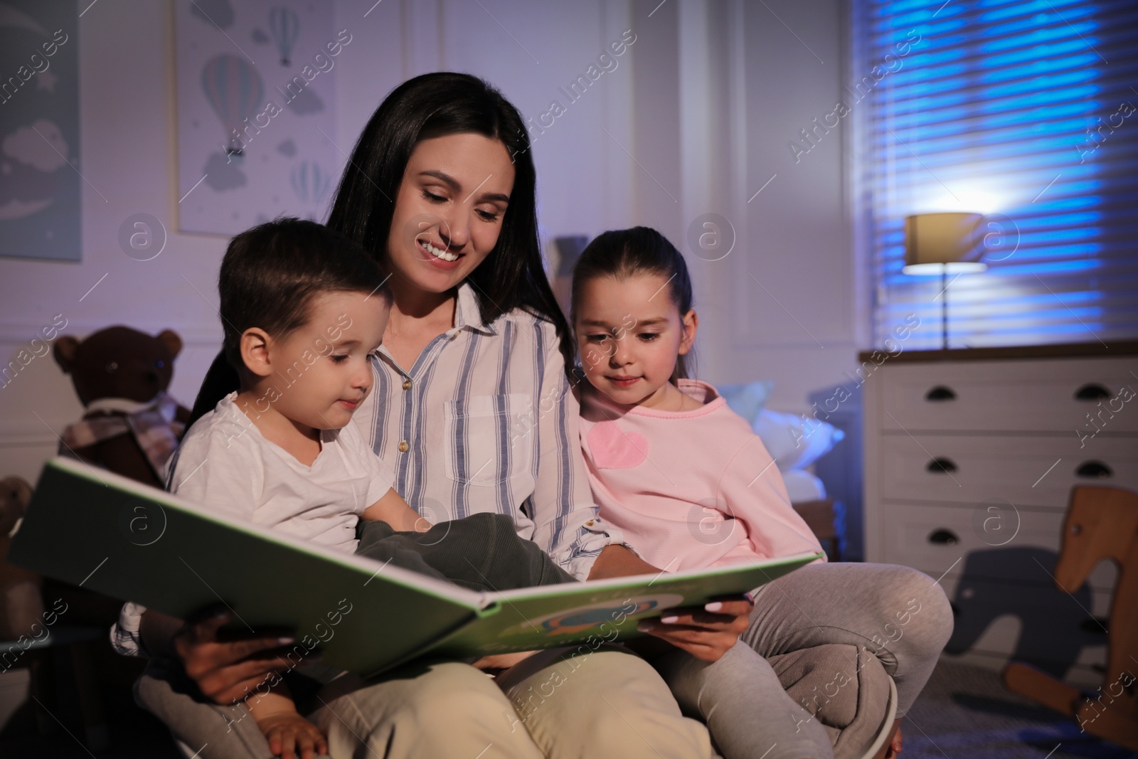 Photo of Mother reading bedtime story to her children at home