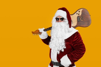 Santa Claus with electric guitar on yellow background, space for text. Christmas music