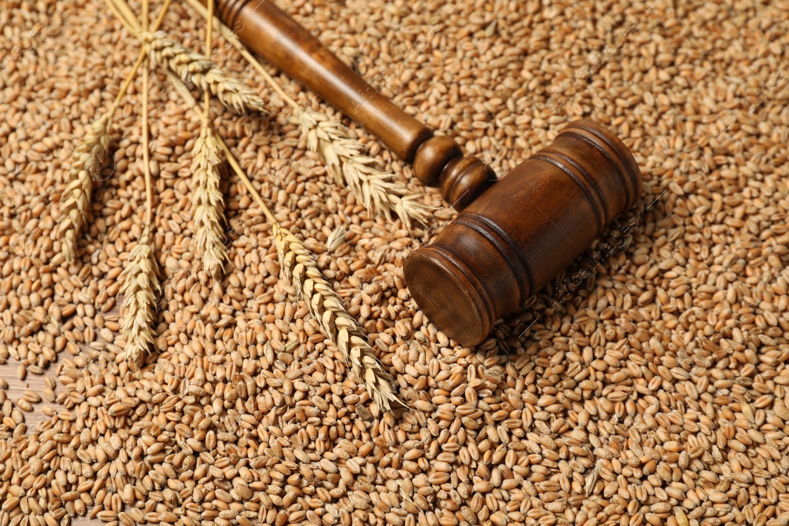 Photo of Wooden gavel and wheat ears on grains. Agricultural deal