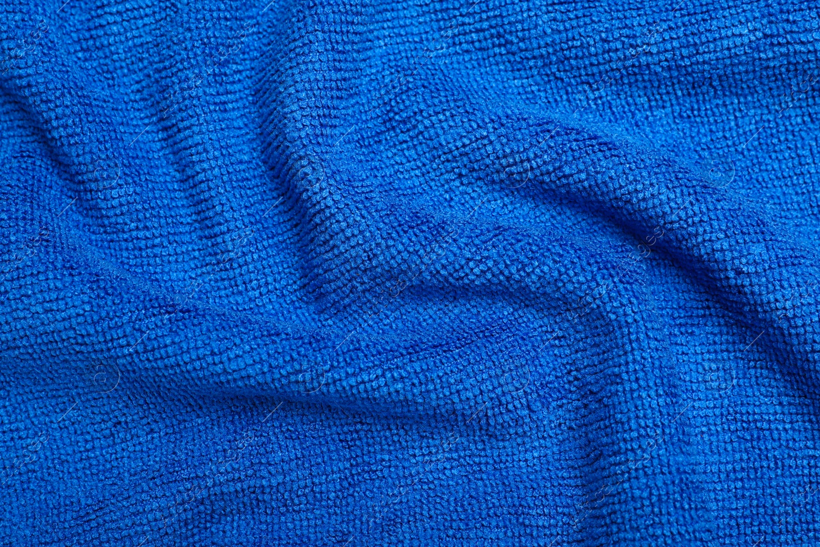 Photo of Crumpled blue microfiber cloth as background, closeup