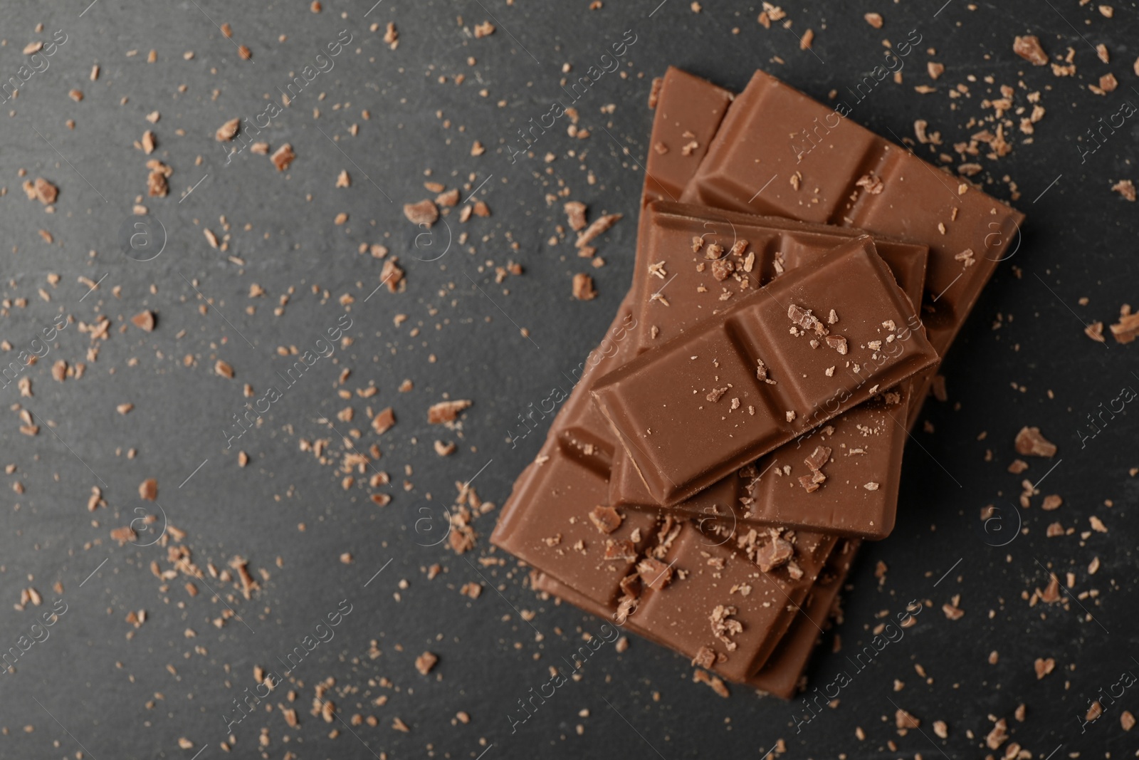 Photo of Pieces of tasty chocolate on grey table, top view. Space for text