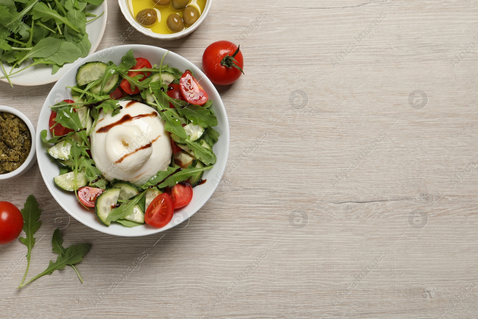 Photo of Delicious burrata salad served on wooden table, flat lay. Space for text