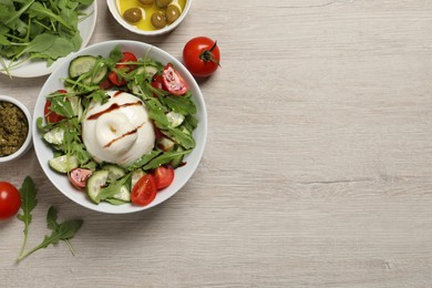 Photo of Delicious burrata salad served on wooden table, flat lay. Space for text