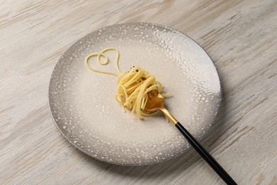 Photo of Heart made with spaghetti and fork on light wooden table