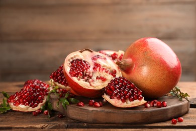 Photo of Delicious fresh ripe pomegranates on wooden table