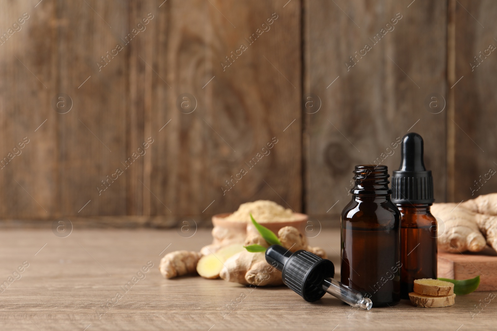 Photo of Ginger essential oil in bottles on wooden table. Space for text