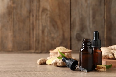 Photo of Ginger essential oil in bottles on wooden table. Space for text