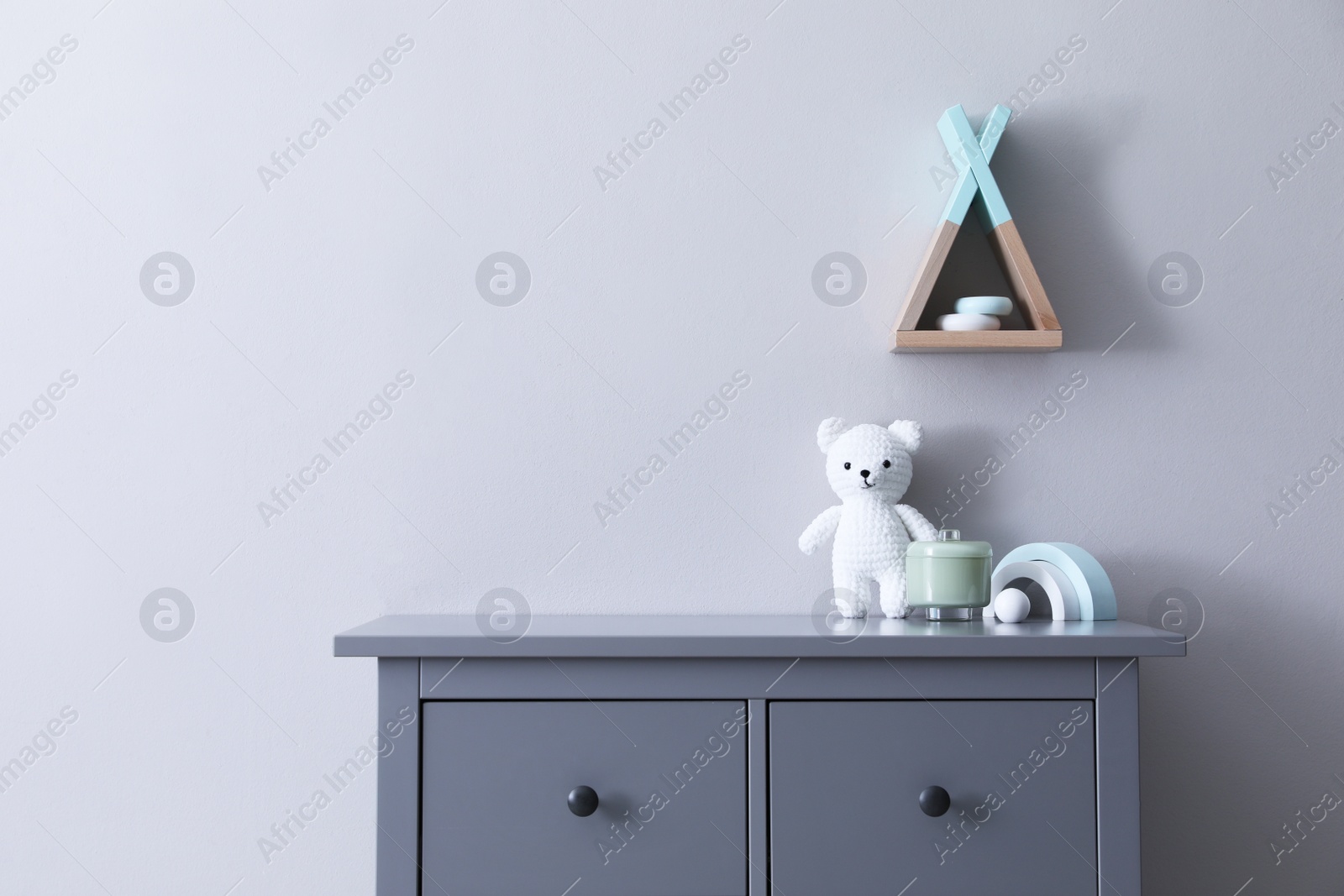 Photo of Child's toys on chest of drawers near light grey wall indoors