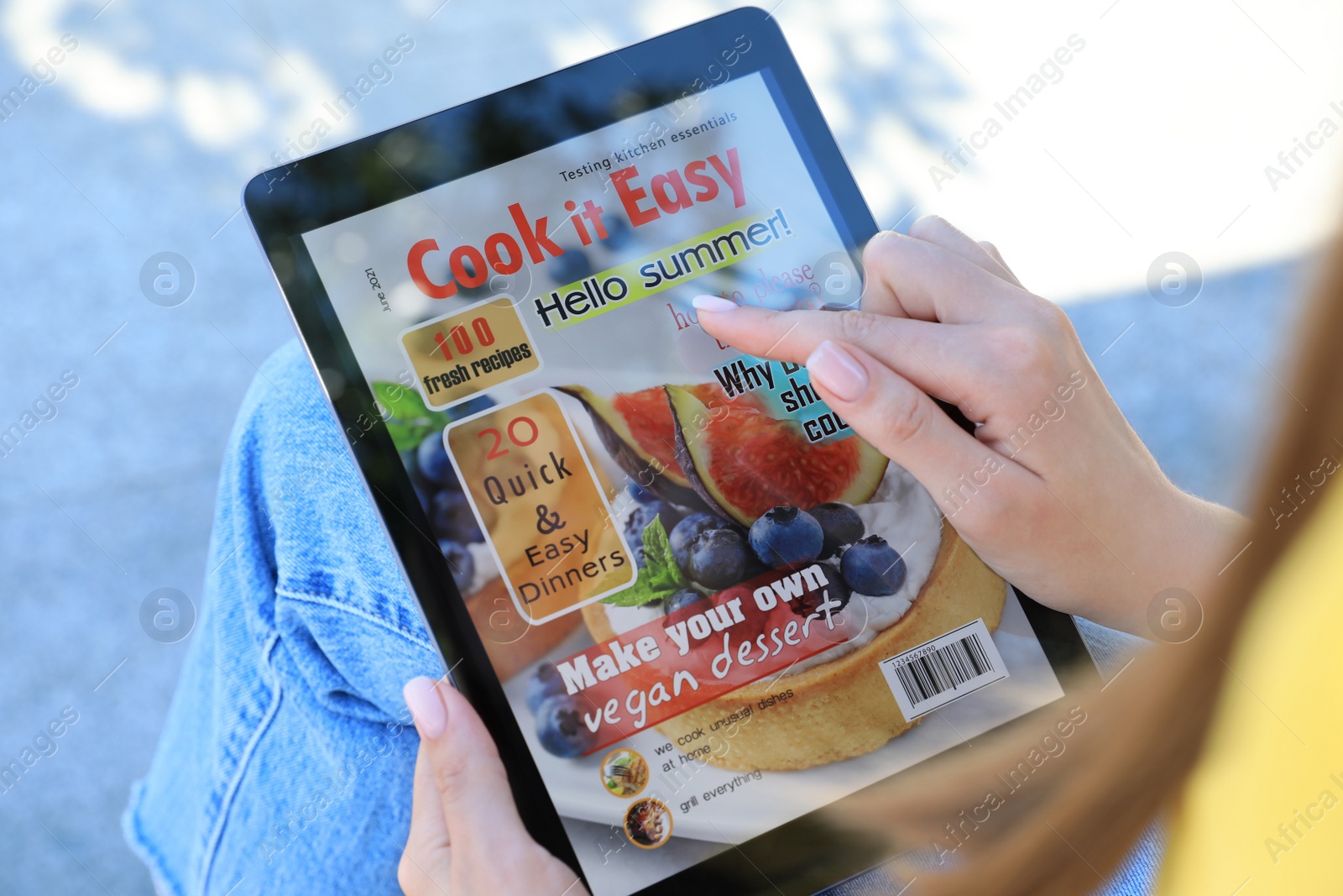 Photo of Woman reading online magazine on tablet outdoors, closeup