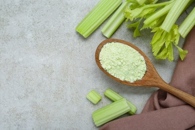 Natural celery powder in wooden spoon and fresh stalks on grey table, flat lay. Space for text