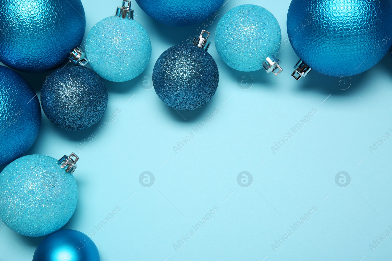 Photo of Christmas balls on light blue background, top view. Space for text