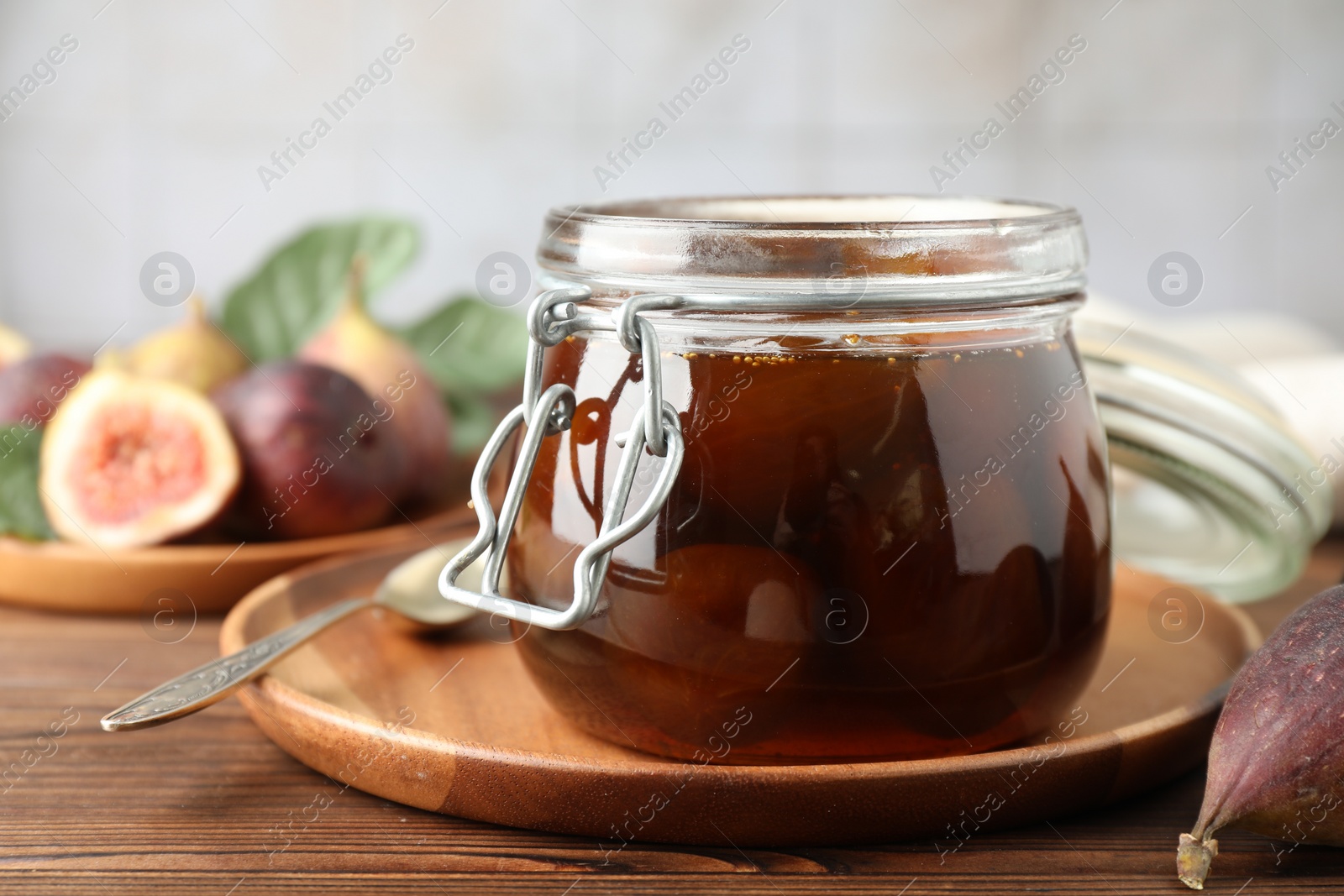 Photo of Jar of tasty sweet fig jam on wooden table