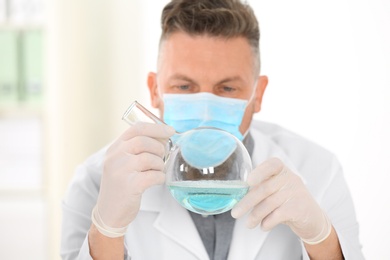 Male scientist with protective mask working in laboratory. Research and analysis