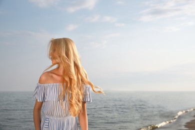 Beautiful young woman near sea on sunny day, space for text