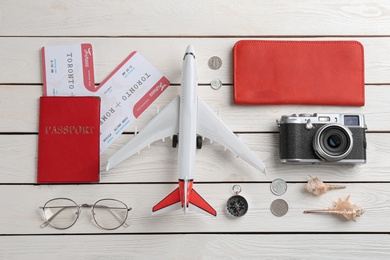 Flat lay composition with toy airplane and travel items on white wooden background