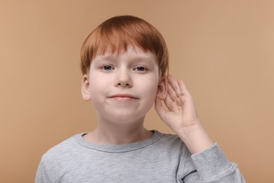 Photo of Little boy with hearing problem on pale brown background