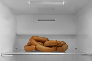 Tasty sausages on shelf of modern refrigerator