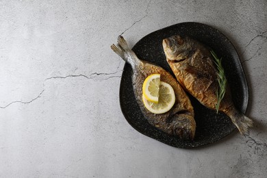 Delicious dorado fish with rosemary and lemon on light grey table, top view. Space for text