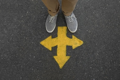 Photo of Man standing near arrow on asphalt, top view