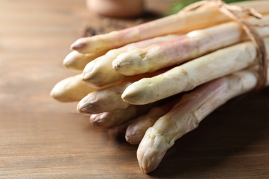 Photo of Bunch of fresh white asparagus on wooden table, closeup