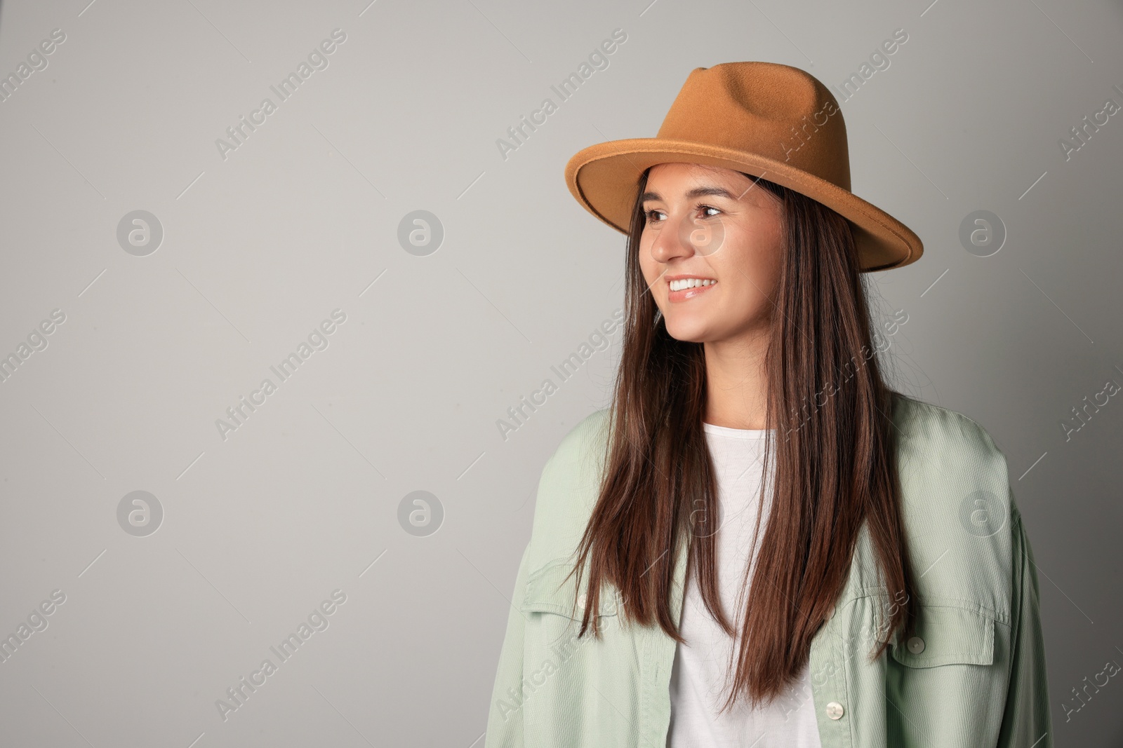 Photo of Smiling young woman in stylish outfit on light background. Space for text