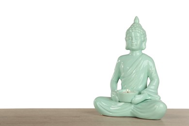 Photo of Beautiful ceramic Buddha sculpture with burning candle on wooden table against grey background. Space for text