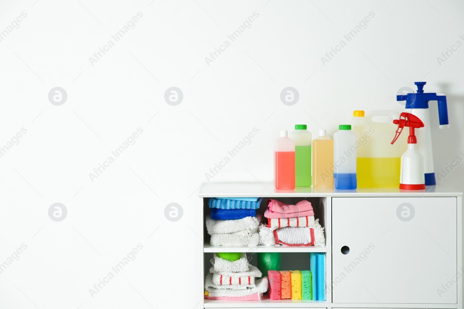 Photo of Cabinet with different cleaning supplies on white background. Space for text