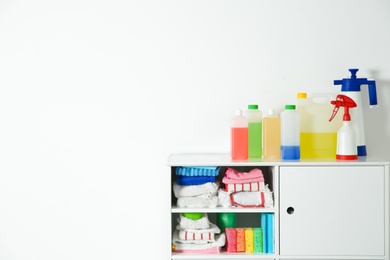 Photo of Cabinet with different cleaning supplies on white background. Space for text