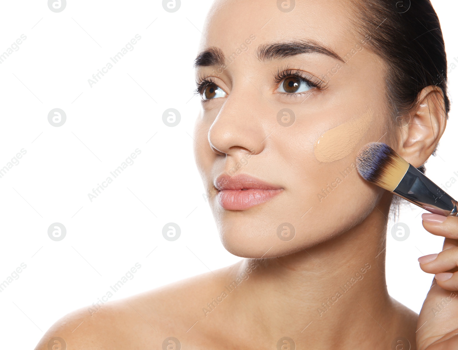 Photo of Young woman applying foundation on her face against white background