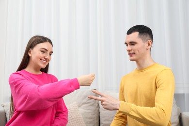 Happy people playing rock, paper and scissors in room