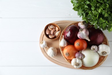 Photo of Fresh raw garlic, onions and parsley on white wooden table, top view. Space for text