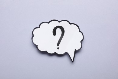 Paper speech bubble with question mark on light grey background, top view