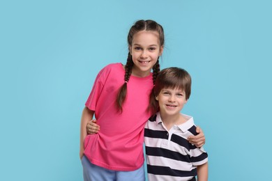 Photo of Happy brother and sister hugging on light blue background