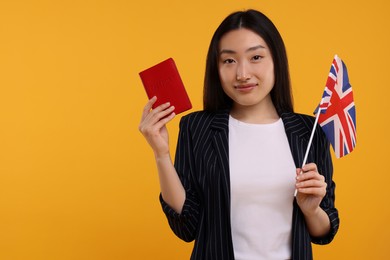 Photo of Immigration to United Kingdom. Woman with passport and flag on orange background, space for text