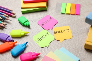 Photo of Sticky notes with words Diversity, Equality, Inclusion and stationery on wooden table